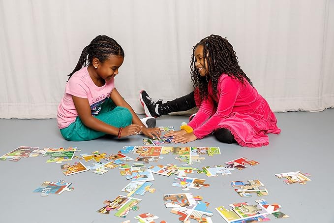 Two young girls playing with colorful cards on a gray floor.