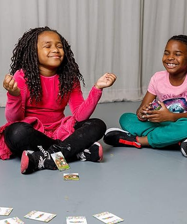 Two children sitting on the floor with cards spread out in front of them, smiling.