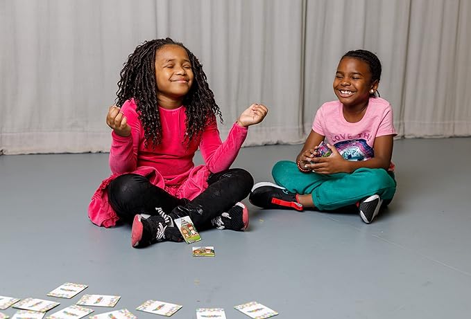 Two children sitting on the floor with cards spread out in front of them, smiling.