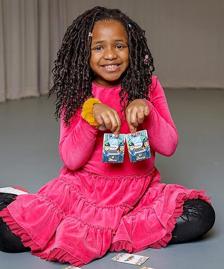 Child in a pink dress sitting on the floor holding two culzzle puzzle pieces.
