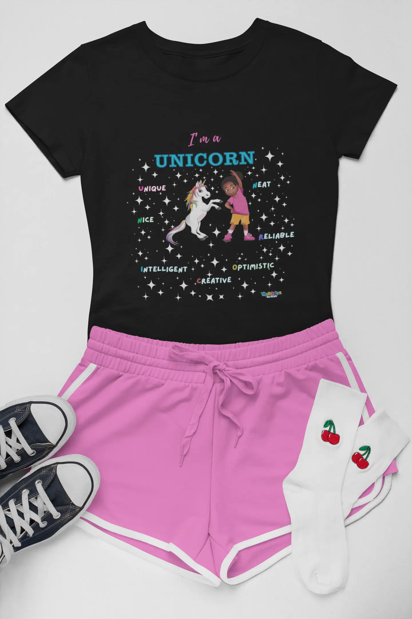 Culzzles Black t-shirt with unicorn graphic, pink shorts, black sneakers, and white socks with cherries on a light gray background.