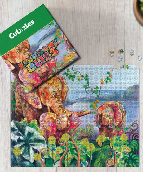 Jigsaw puzzle with elephants and foliage on a wooden surface, featuring the 'Coluzzles' brand.
